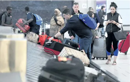  ?? JUSTIN TANG/.THE CANADIAN PRESS ?? Travellers pick up their luggage at a baggage carousel at the Ottawa Airport on Tuesday. The federal government is introducin­g legislatio­n for a passenger bill of rights that will set guidelines for how airlines passengers are treated.