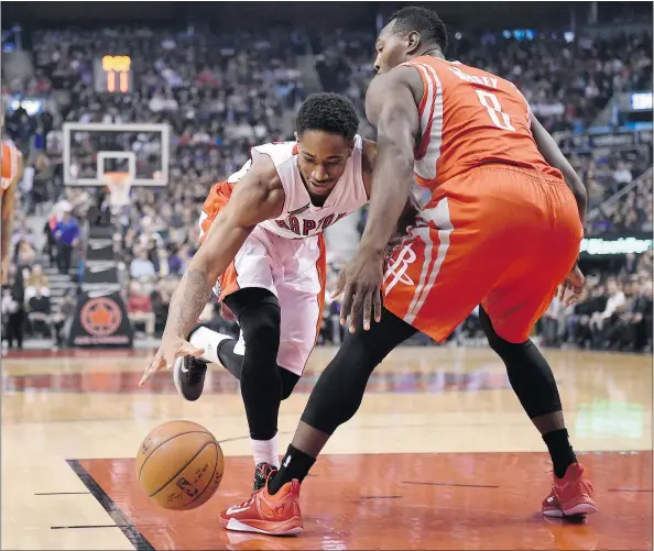  ?? — THE CANADIAN PRESS/FRANK GUNN ?? Toronto Raptors’ DeMar DeRozan and Houston Rockets’ Joey Dorsey battle for a loose ball during first half play in Toronto on Monday. DeRozan scored a career-high 42 points and added 11 rebounds in the Raptors’ 99-96 triumph.