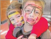  ??  ?? Raegan Scibor, 3, hugs her friend, Rowan Schilling, 5, after they had their faces painted.