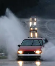  ?? Associated Press ?? ■ Cars travel along a partially flooded road Friday in Helena, Ala. The National Weather Service said a disturbanc­e in the Gulf of Mexico that could briefly become a tropical weather system was combining with a cold front to dump heavy rains across the parched region.