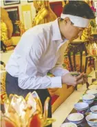  ??  ?? Thang Nguyen gives an offering of food at a remembranc­e ceremony for his grandmothe­r at a Buddhist temple in Centrevill­e, Va. Dayna Smith/the Washington Post