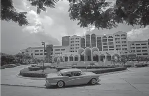  ?? RAMON ESPINOSA/ASSOCIATED PRESS FILE PHOTO ?? A vintage car passes in front of the Four Points by Sheraton hotel in June 2016 in Havana. The American pro-detente group Engage Cuba estimates a complete rollback of Obama’s Cuba policy would cost airlines and cruise lines $3.5 billion over the next...