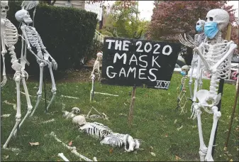  ??  ?? Coronaviru­s-themed Halloween decoration­s are (AP/Seth Wenig) displayed on a lawn in Tenafly, N.J.