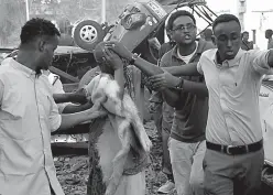  ?? Associated Press ?? Somalis help a wounded man who was injured in a car bomb that was detonated on Saturday in Mogadishu, Somalia.