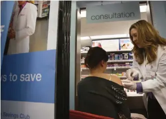  ?? AP PHOTO ?? Pharmacist Stacia Woodcock administer­s a flu shot last month for Walgreens in New York. The pharmacy said it has seen higher sales of flu-related drugs as well as vaccines.