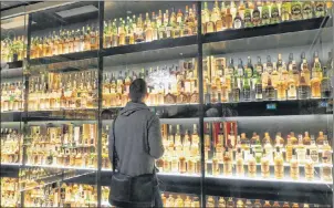  ?? PHOTO BY JOHN NOWLAN ?? Examining a small portion of the World’s Biggest Whisky Collection.