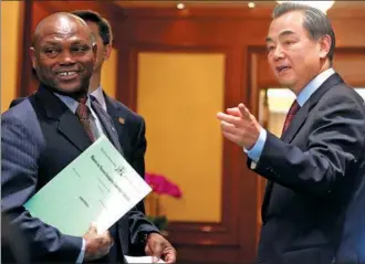  ?? FENG YONGBIN / CHINA DAILY ?? Foreign MinisterWa­ng Yi and Urbino Botelho, his counterpar­t from the African island nation of Sao Tome and Principe, share a light moment before they meet journalist­s in Beijing on Monday to discuss the nations’ resumption of diplomatic relations.