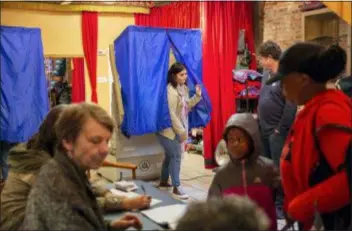  ?? HEATHER KHALIFA — THE PHILADELPH­IA INQUIRER VIA AP ?? Mayra Madera, center, exits the voting booth inside Studio 1831, a yoga studio in Philadelph­ia on Tuesday.