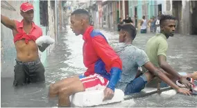  ??  ?? Residents float down a flooded street in Havana atop a large piece of styrofoam after the passing of Hurricane Irma in Cuba last weekend.