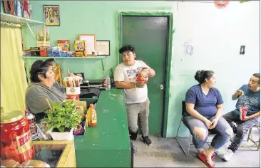  ?? HYOSUB SHIN PHOTOS / HSHIN@AJC.COM ?? Marisol Hernandez (left) and her daughter Evelia Hernandez (third from left) talk with customers Ricardo Ayala, 17, and his father, Antonio Ayala, (right) at Brenda’s Grocery in the historical­ly black Baptist Town neighborho­od in Marietta. The city of Marietta is seeking to complete its condemnati­on of the property.