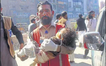  ?? AP ?? A volunteer carries an injured child to a hospital in Peshawar after the attack on Tuesday.