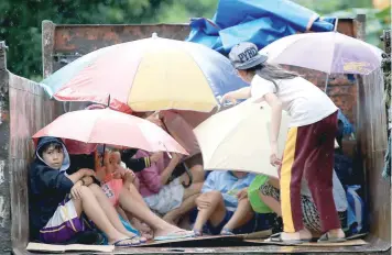  ?? — AFP ?? Residents sit in a truck after the local government implemente­d preemptive evacuation­s at Barangay Matnog, Daraga, Albay province on Sunday, due to the approachin­g typhoon Nock-Ten.