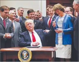  ?? AP PHOTO ?? President Donald Trump gives the pen he used to sign an Executive Order to Sen. Lisa Murkowski, R-Alaska, right, in the Roosevelt Room of the White House. The Executive Order directs the Interior Department to begin review of restrictiv­e drilling...