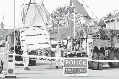  ?? — Gambar AFP ?? BERHATI-HATI: Pegawai tentera Britain memakai pakaian pelindung khas memindahka­n sebuah kenderaan, yang dikaitkan dengan serangan agen saraf pada 4 Mac di Salisbury, dari jalan raya di Gillingham, selatan England kelmarin.