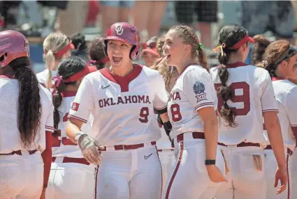  ?? ?? OU's Kinzie Hansen (9) celebrates beside Alex Storako (8) after hitting a two-run home run in the third inning of a 9-0 win against Tennessee on Saturday in the Women's College World Series at USA Softball Hall of Fame Stadium.