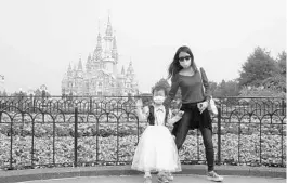  ?? SAM MCNEIL/AP ?? A young visitor, wearing a face mask, waves at the Disneyland theme park in Shanghai. Visits will be limited initially and must be booked in advance, and the company said it will increase cleaning and require social distancing in lines for the various attraction­s.