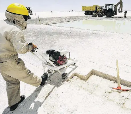  ?? AIZAR RALDES/AFP/GETTY IMAGES FILES ?? A worker cuts salt bricks at the state-run lithium plant at Bolivia’s Uyuni Salt Flats. There are growing fears that the supply and demand forecasts for lithium are out of whack, and that prices will crash, even as massive growth is forecast for the metal.