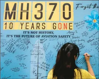  ?? AP ?? A woman writes on message board during the 10th annual remembranc­e event for flight MH370 at a shopping mall near Kuala Lumpur, Malaysia Sunday.