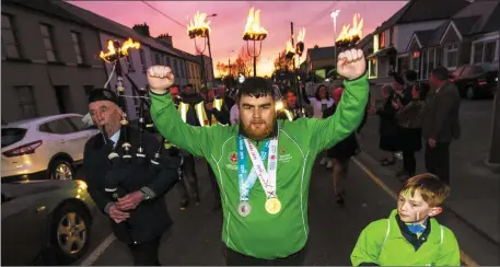  ?? Photo by: John Reidy ?? There was a hero’s welcome home on Saturday night for Castleisla­nd’s Special Olympics World Games gold and silver medalist, Gary O’Sullivan with a torch-lit parade through his home town. Gary is flanked here by his cousin, Jamie Davis and Piper, Noel O’Mahony.