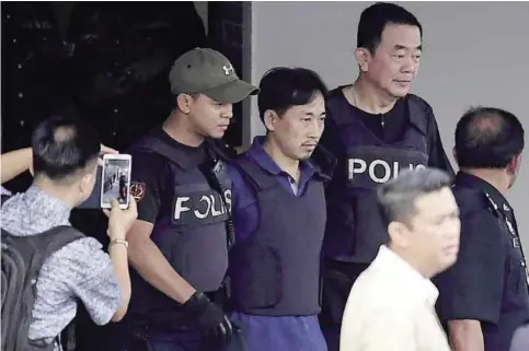  ??  ?? SEPANG: North Korean national Ri Jong Chol, centre, is escorted with a heavy police presence as he leaves the Sepang police headquarte­rs in Sepang yesterday. —AFP