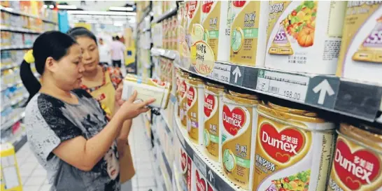  ?? Photo: REUTERS ?? Health issue: A sales assistant, front, helps a customer select milk powder at a supermarke­t in Hefei, in China’s Anhui province.