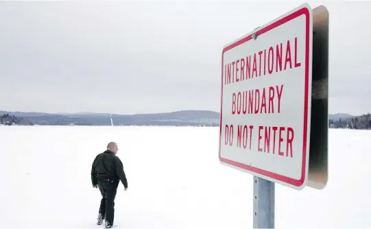  ?? JOE RAEDLE / GETTY IMAGES ?? U. S. Border Patrol Agent Andrew Mayer walks onto a frozen lake that divides Canadian territory to the right and the U. S., near Norton, Vt.