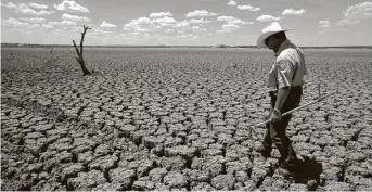  ?? Tony Gutierrez / Associated Press file ?? Texas State Park Police Officer Thomas Bigham examines the cracked lake bed of O.C. Fisher Lake in San Angelo in 2011. Climate change has been debated for decades.