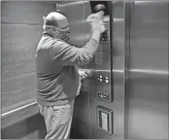  ?? SEAN D. ELLIOT/THE DAY ?? Johan Liebenberg, general manager of the Hilton Mystic, disinfects the elevator control panel Friday. He said he often carries a bottle of disinfecta­nt with him as he makes rounds of the hotel during the closure and cleans hightouch surfaces.