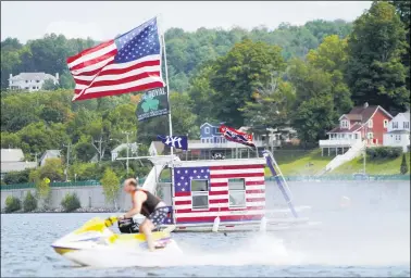  ?? BEN GARVER — THE BERKSHIRE EAGLE VIA AP ?? A jet skier passes a patriotic shanty-boat owned by AJ Crea on Pontoosuc Lake on Labor Day in Pittsfield, Mass.