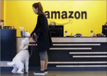  ?? ELAINE THOMPSON — THE ASSOCIATED PRESS FILE ?? An Amazon employee gives her dog a biscuit as the pair head into a company building, where dogs are welcome, in Seattle. Amazon announced Thursday that it has narrowed its hunt for a second headquarte­rs to 20 locations, concentrat­ed among cities in the...