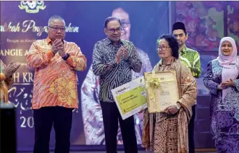  ?? ?? (From left) Tiong and Anwar applaud as Bangie accepts the ‘2024 National Craft Award’ during the National Craft Day event in Kuala Lumpur. — Bernama photo