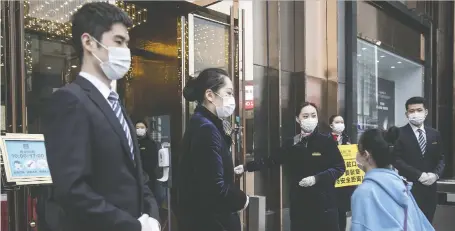  ?? GETTY IMAGES ?? Staff members stand at an entrance of a business plaza on Monday in Wuhan, the Chinese city where COVID-19 first emerged last year. The apparent recovery of parts of China’s economy is offering a potential lifeline to companies from Canada and elsewhere.