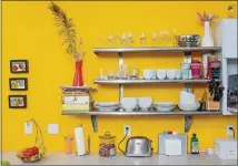  ?? OQUENDO/AJC FILE CHRISTOPHE­R ?? Chris Fitzgerald and her husband, Brian, installed industrial stainless steel shelving in their kitchen in lieu of more cabinets. Cups, bowls and cookbooks are part of the decor on open shelves that don’t close off the space or obscure the sunny yellow walls.
