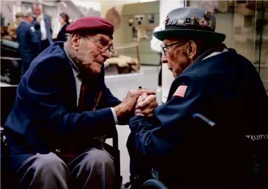  ?? THOMAS PADILLA/ASSOCIATED PRESS ?? British veteran Bill Gladden (left) greeted US veteran Jack M. Larson in Benouville, Normandy, on Monday. At left, US infantryme­n waded through the surf at Normandy in the days following the Allies’ June 1944 D-Day invasion.