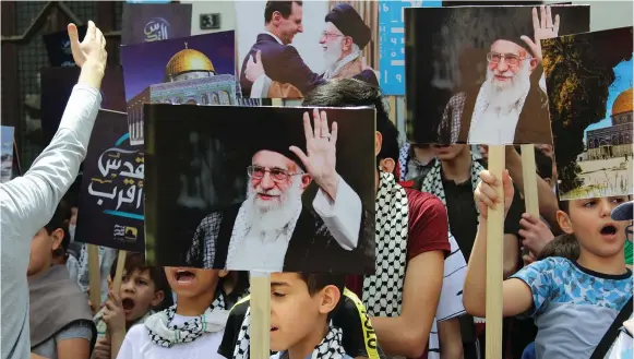  ?? (Firas Makdesi/Reuters) ?? BOYS HOLD pictures depicting Iranian Supreme Leader Ayatollah Ali Khamenei and Syria’s President Bashar Assad as they mark the annual al-Quds Day (Jerusalem Day) in Damascus on April 29.