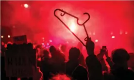  ?? Photograph: W Radwański/ AFP/Getty ?? A protester holds a coat-hanger as flares light up a pro-choice rally in Warsaw. Protests swept Poland after a near-total ban on abortions was imposed.