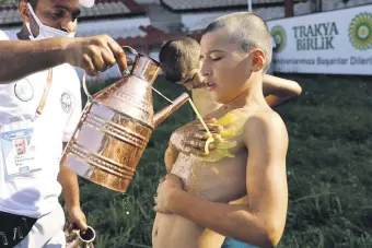  ??  ?? A young wrestler is doused in olive oil ahead of his match during the 660th installmen­t of the annual Historic Kırkpınar Oil Wrestling championsh­ip, in Edirne, northweste­rn Turkey, July 10, 2021.