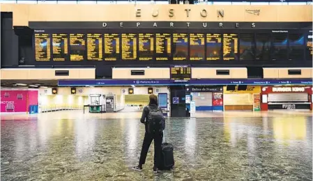  ?? STEFAN ROUSSEAU AP ?? A passenger at Euston station in London looks at the departures board on the first day of a rail strike on Tuesday. Britain’s biggest rail strike in decades began after talks between a union and train companies failed to reach a settlement over pay and job security.