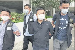  ?? THE ASSOCIATED PRESS ?? Ryan Law, second from right, Apple Daily’s chief editor, is arrested by police officers in Hong Kong on Thursday.