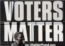  ?? Gerry Broome/Associated Press ?? A man wearing a mask gathers with a group in support of Black Voters Matter at the Graham Civic Center polling site in Graham, N.C. in November 2020.