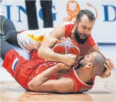  ?? FOTO: DPA ?? Seltener Nahkampf im Basketball: Bastian Doreth landet auf dem Serben Stefan Peno, behält aber Ball und Kopf unter Kontrolle.