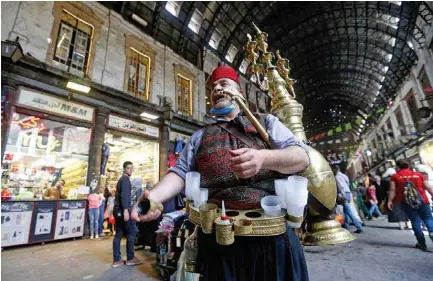  ??  ?? Ishaaq Kremed, a tamarind juice seller, calls on customers in the covered Hamidiyah market in the old part of the capital Damascus. — AFP photos