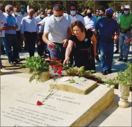  ??  ?? Kutlu Adalı’s wife İlkay places flowers on the grave of her husband who was murdered in 1996