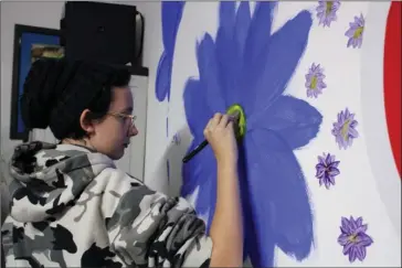  ?? The Sentinel-Record/Tanner Newton ?? FLOWERS ON THE WALL: A high school student in the UCA Upward Bound program paints a flower on a wall at the Cutwell 4 Kids studio on Nov. 23. Twenty-five other students also painted on the walls that day.