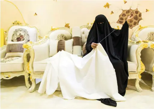  ??  ?? Ayisha Ghareb, sews a shroud at her home in Kalba, above, in an act of love and respect for the UAE’s martyrs, left Christophe­r Pike, Pawan Singh / The National