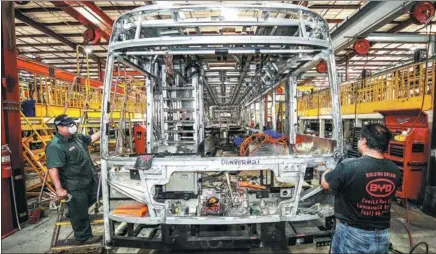  ?? XINHUA ?? Two employees polish the frames of an electric bus at BYD’s bus factory in Lancaster, California in the United States.