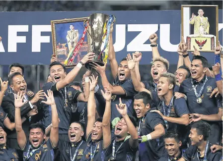  ?? EPA ?? Coach Kiatisak Senamuang, right, celebrates under a portrait of the late King Bhumibol Adulyadej with his players after Thailand won the 2016 Suzuki Cup.