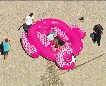  ?? KTLA ?? POLICE ASK three men on the L.A. River to deflate their raft. A trio last week attempted a similar stunt.