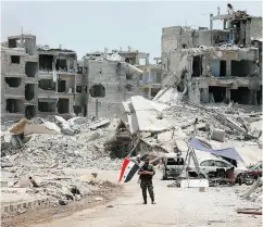  ?? LOUAI BESHARA / AFP / GETTY IMAGES ?? A member of the pro-government forces holds his national flag near Damascus. The UN said Syrian army and rebel forces committed war crimes during the battle.