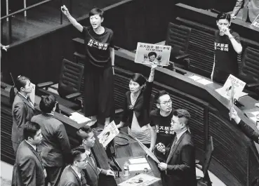  ?? Mark Schiefelbe­in / Associated Press ?? Chanting slogans and holding up doctored images of Hong Kong Chief Executive Carrie Lam with bloody hands, pro-democracy lawmakers protest Lam’s annual policy speech Wednesday in the Legislativ­e Council.